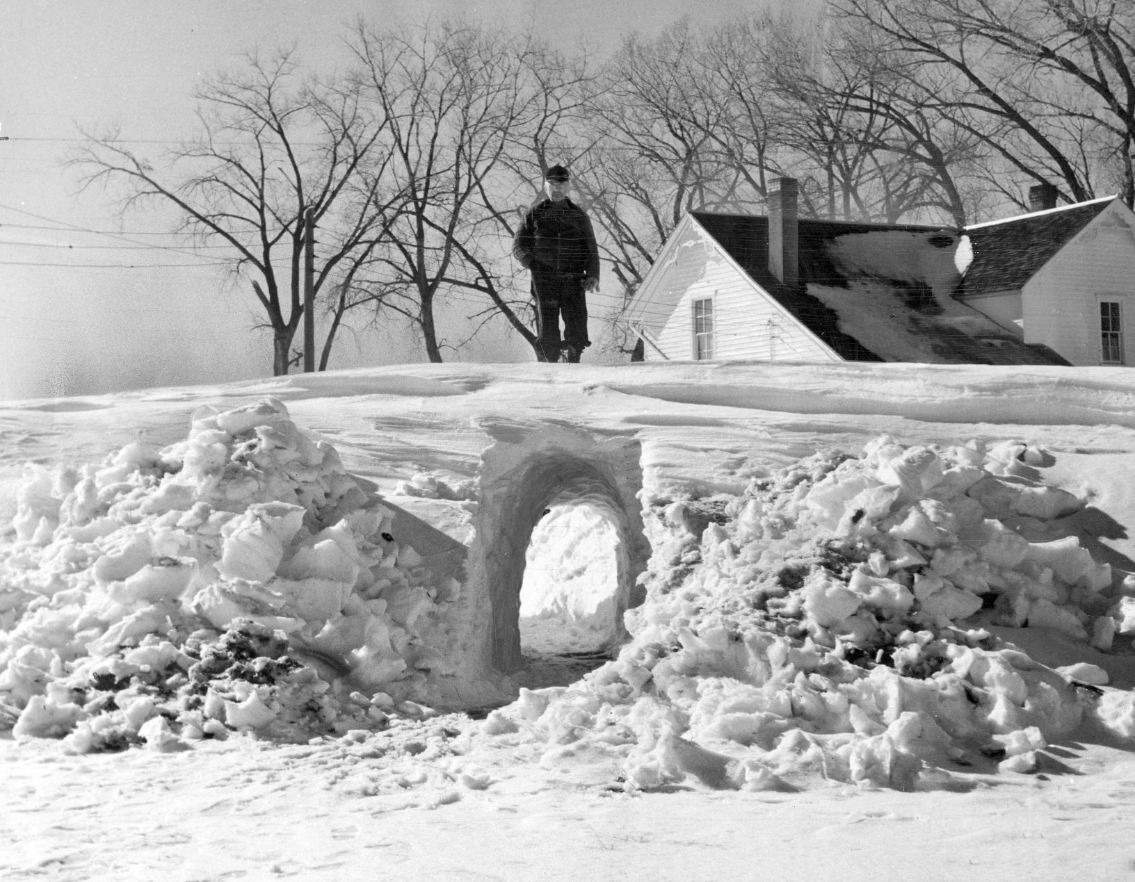 Farmer E.F. Eberly stands above the tunnel he made through 15 foot snowdrifts on his farm 2 miles southeast of Norfolk. The tunnel was 15 feet long and 7 feet high which he could walk through without stooping to get from the house to the barn to feed his livestock. Published Feb. 17, 1949.